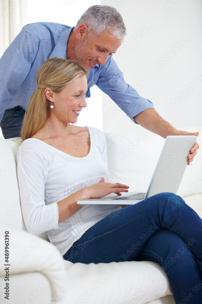 密切关注网上购物……一位漂亮的年轻女子与丈夫一起使用笔记本电脑