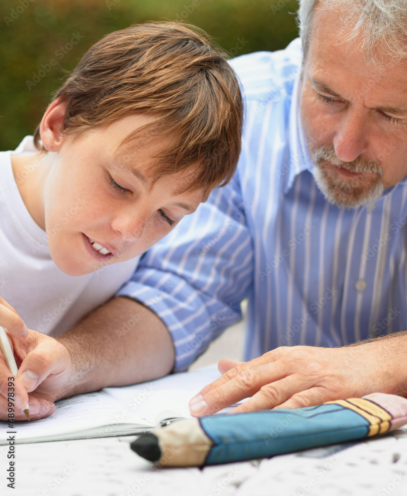 帮他做作业。一个父亲帮儿子做作业的镜头。