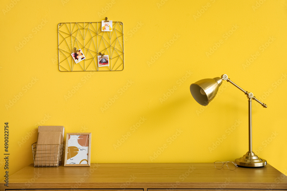 黄色墙壁附近有金色灯的木制桌子