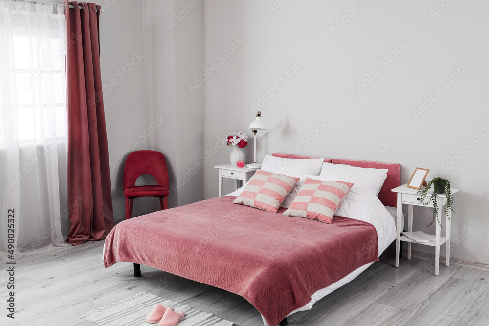 舒适的床、床头柜和椅子靠近浅色墙壁