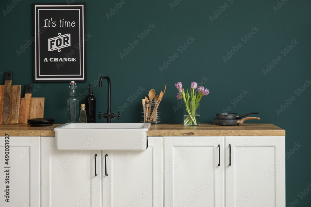 带水槽的柜台、花瓶里的郁金香和靠近彩色墙的厨房用具