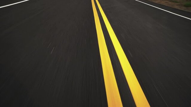 Front pov view of fast car driving on asphalt road with double yellow lines converge
