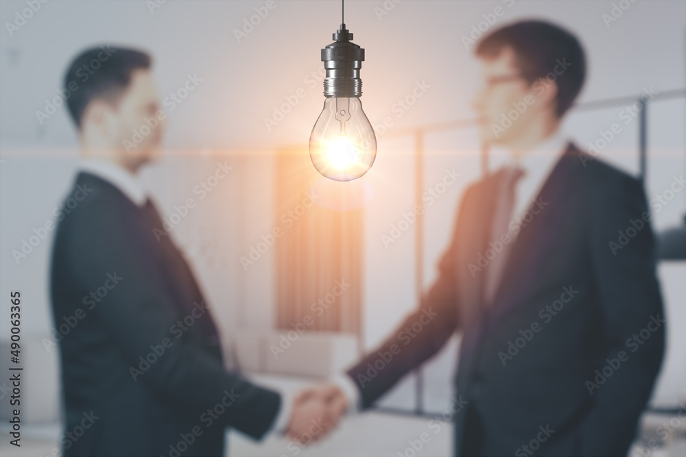 Blurry businesspeople shaking hands together on abstract office interior background with glowing lig