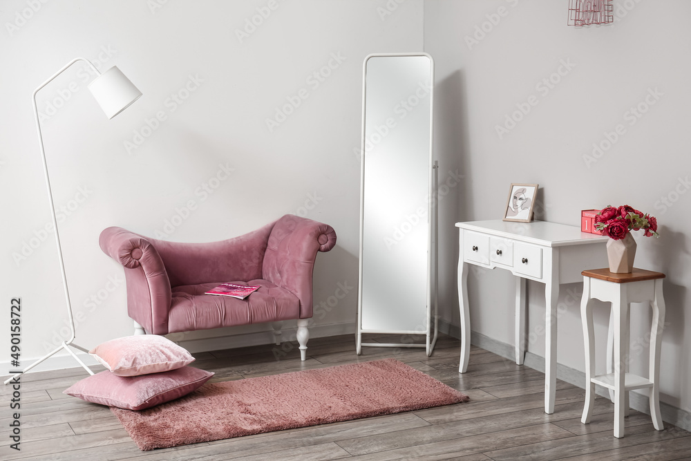 时尚房间的内部，配有粉色扶手椅、镜子和桌子