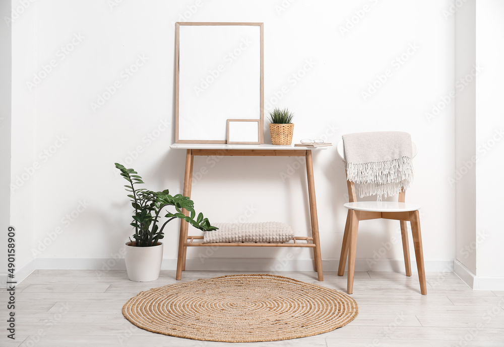 Interior of light room with wooden chair and table with blank photo frames