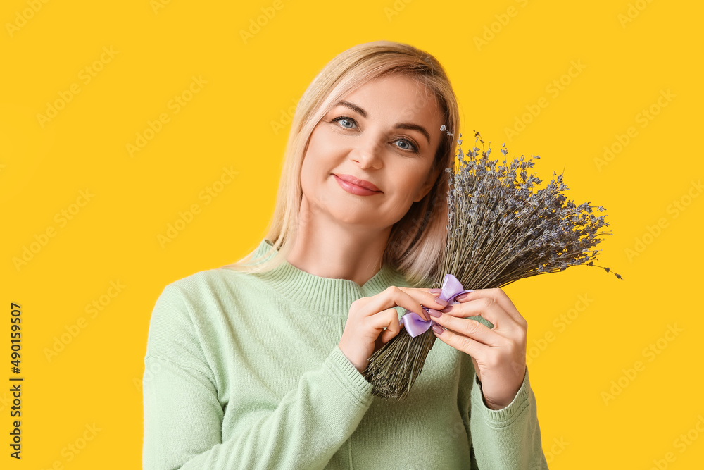 Beautiful woman with bouquet of lavender flowers on yellow background