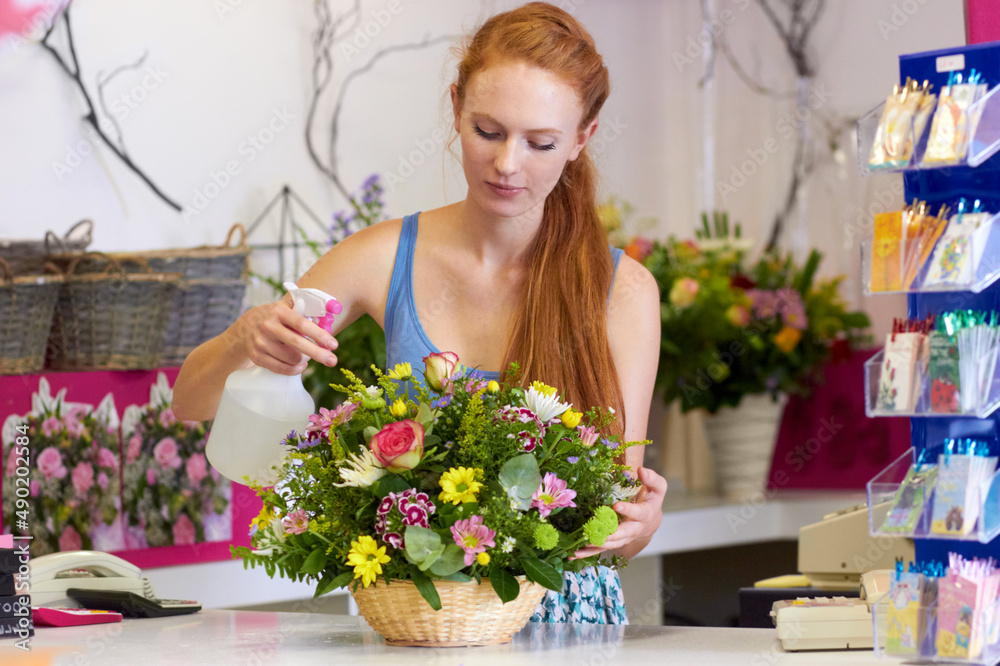 利用自己的技能取得成功。一位年轻的花店老板在她的店里的插花上喷水