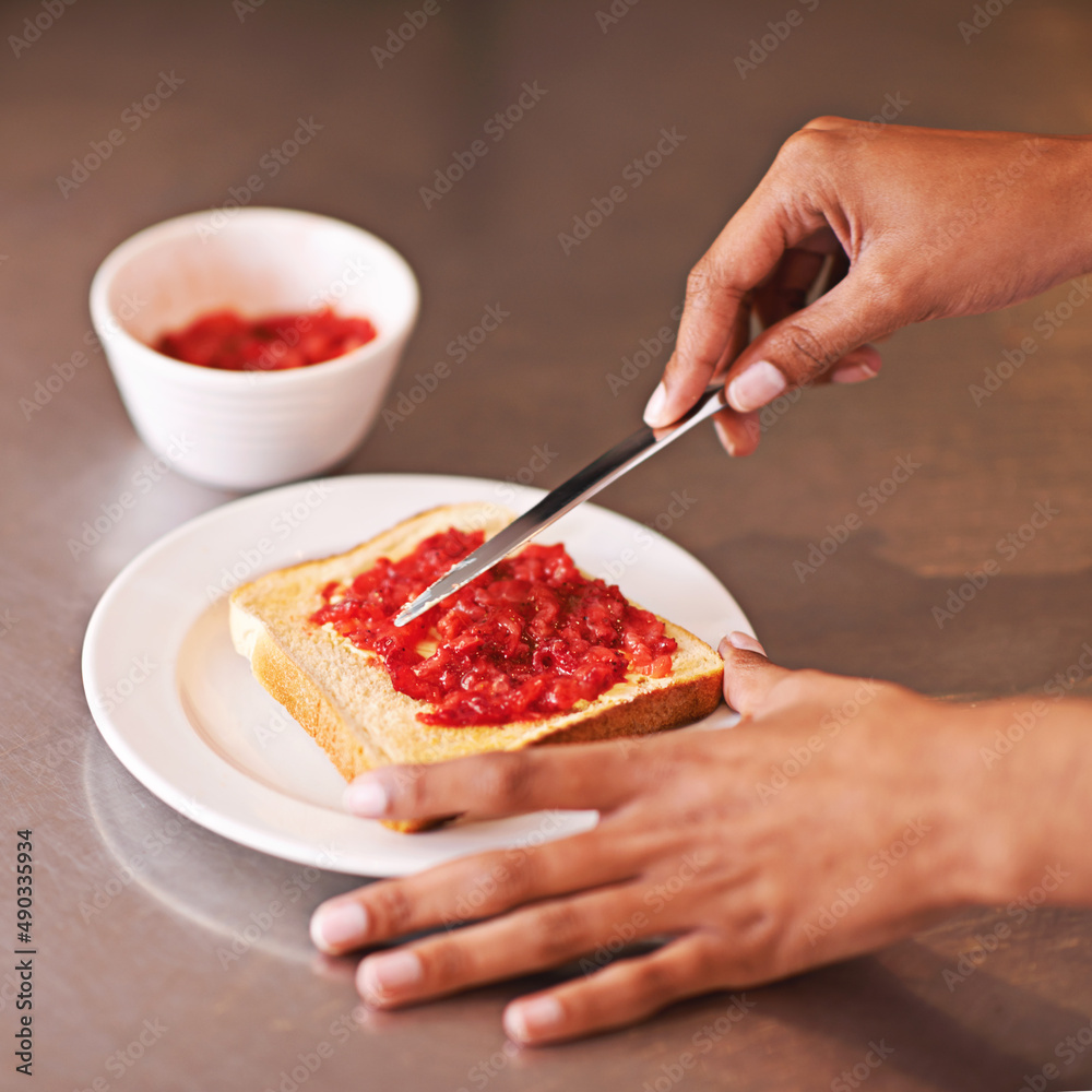 早餐吃水果。一个女人在吐司上涂水果酱的裁剪镜头。