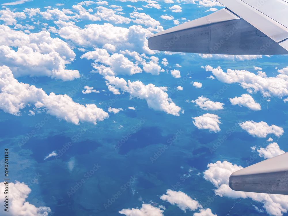 从飞机窗户到机翼、天空、云层和地面的视图。