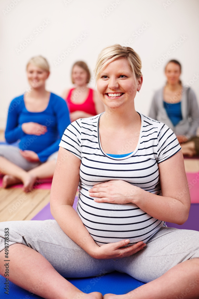我的重点是平静分娩。一群孕妇盘腿坐在瑜伽课上微笑
