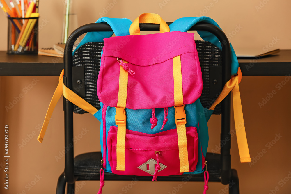 Stylish backpack hanging on chair in room