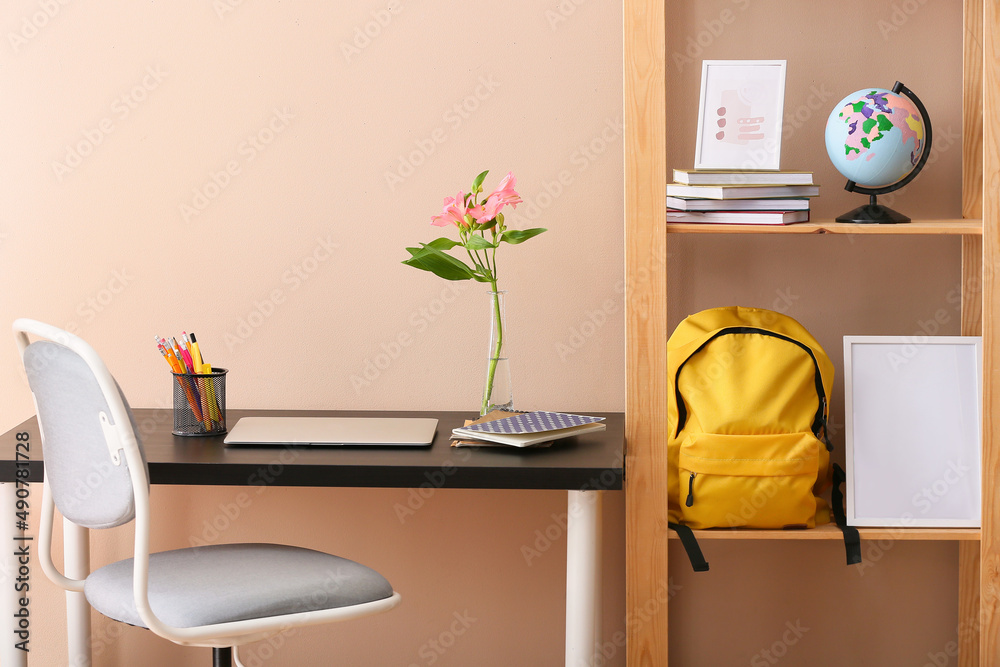 Stylish interior of modern room with backpack, globe and stationery