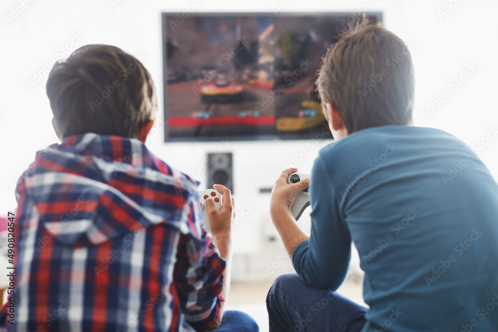 游戏时间。两个男孩在客厅玩电子游戏的后视镜头。