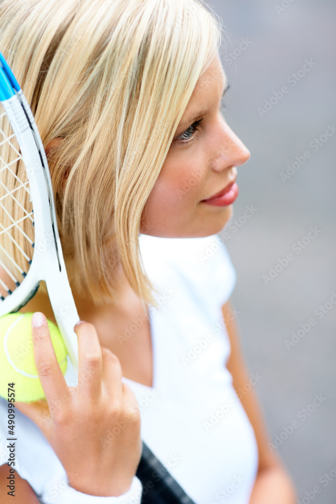 Feeling fully focused on winning. A young female tennis player with her racquet and ball in her hand