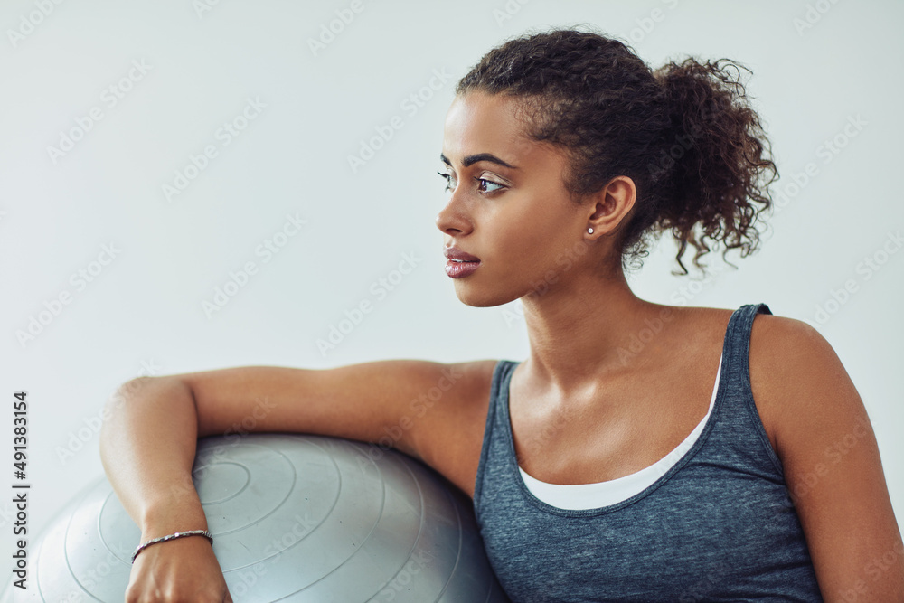 锻炼有助于她理清思路。一位有魅力的年轻女子在运动期间休息的工作室照片