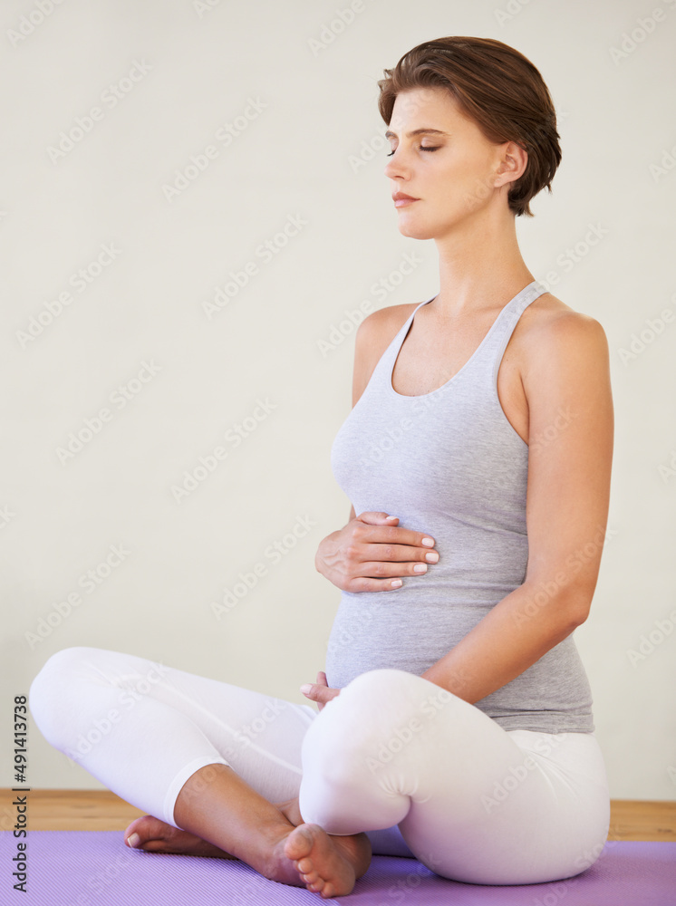 怀孕期间的完美姿势。一位年轻的孕妇坐在运动垫上