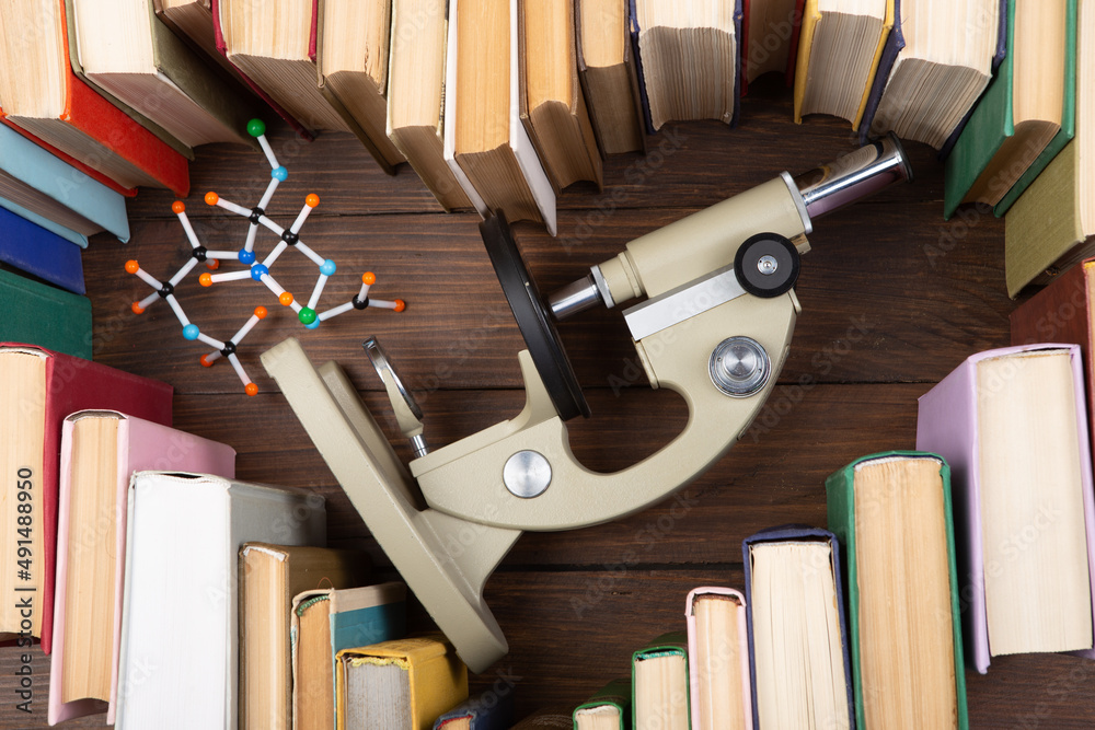热爱科学概念。木制桌子上的书籍、显微镜和分子模型的心形。取一度