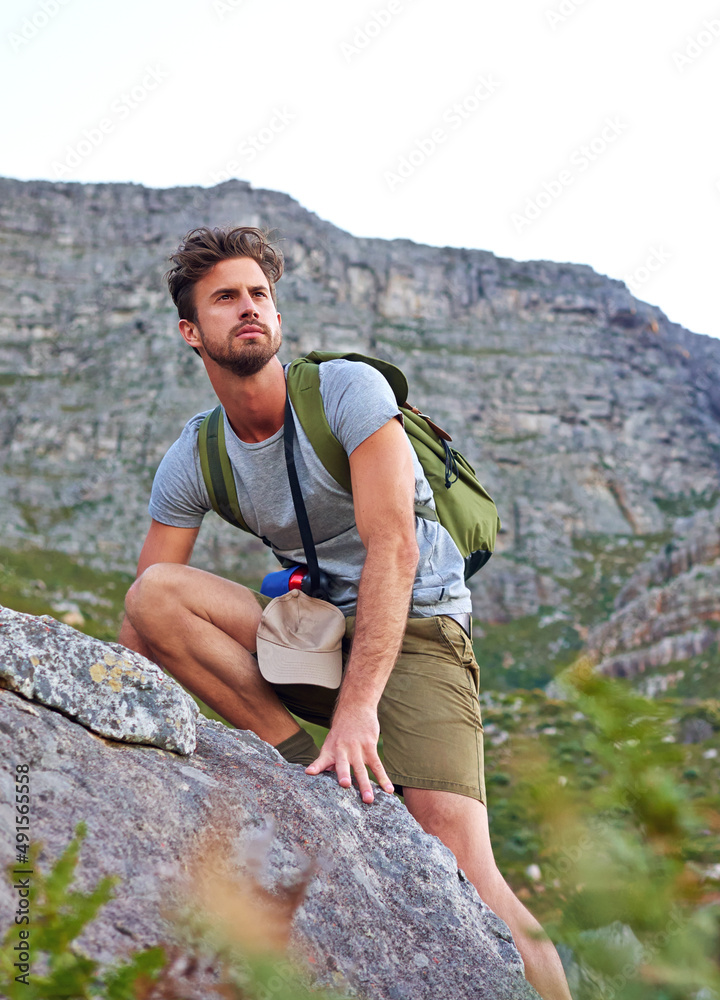 He knows where hes going. Shot of a handsome young man scaling a mountain.