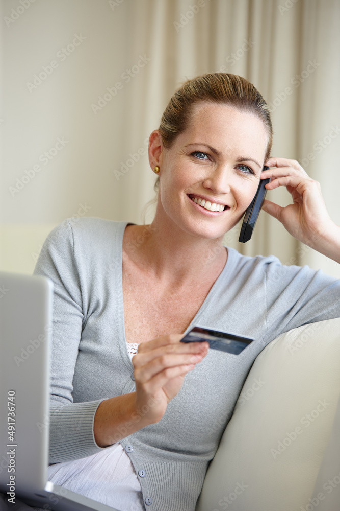 Anything I want at my fingertips. A young woman talking on her cellphone while holding a bank card a