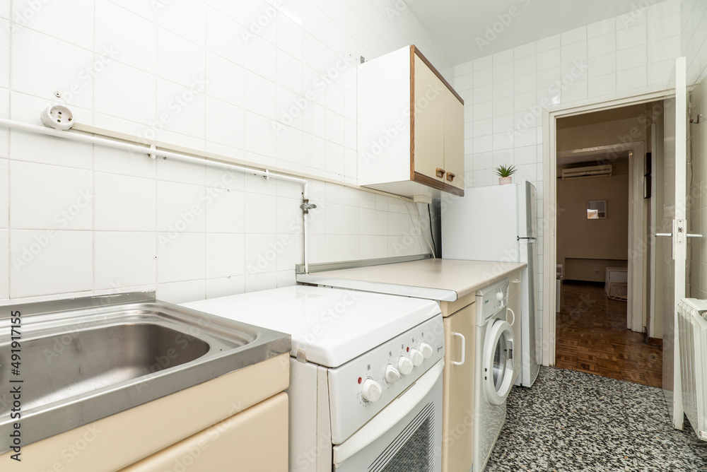 破旧橱柜、水磨石地板和白色方形瓷砖的旧厨房