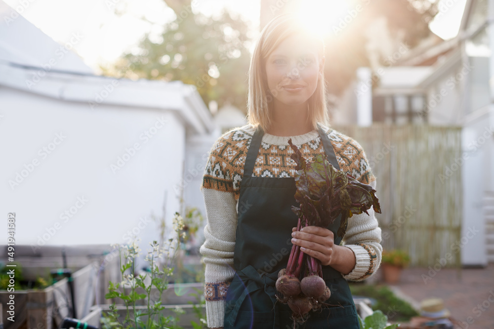 新鲜出炉。一位年轻女子站在花园里，手里拿着新鲜的甜菜根。