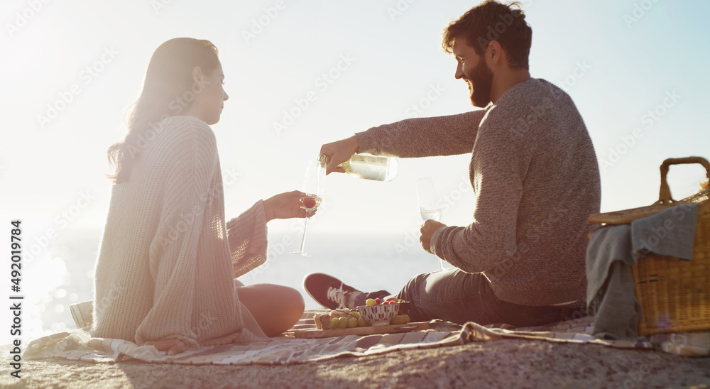 完美的约会确实存在。一对年轻夫妇在海滩野餐的后视镜头。