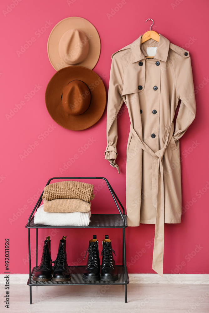 粉色墙上挂着保暖衣服、帽子和风衣的鞋架