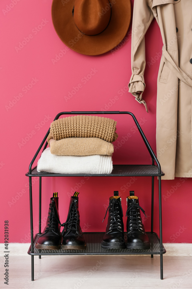 站在粉色墙壁附近，穿着鞋子和一堆温暖的毛衣