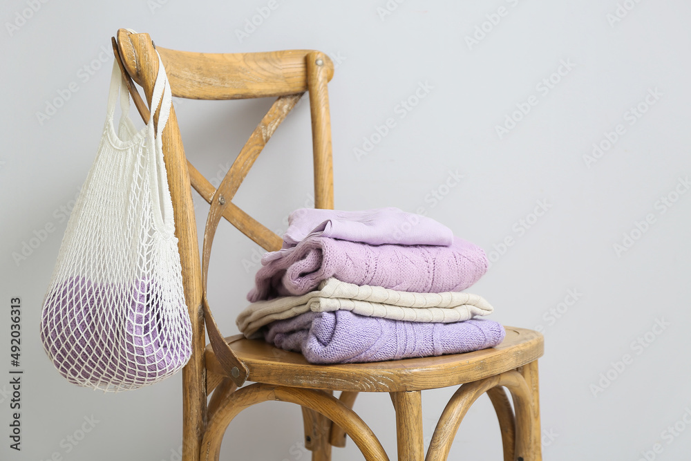 靠近浅色墙壁的带针织毛衣和绳袋的椅子