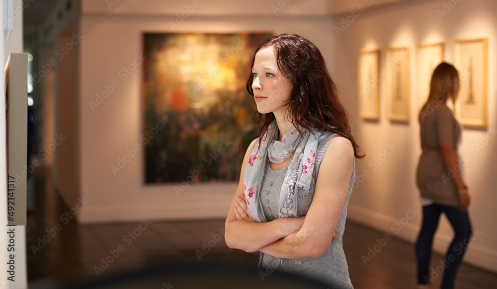 审视大师。一个年轻女人在画廊里看画的镜头。