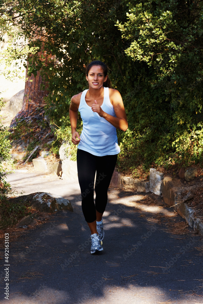 Young woman jogging. Full length of young healthy woman jogging outdoors.
