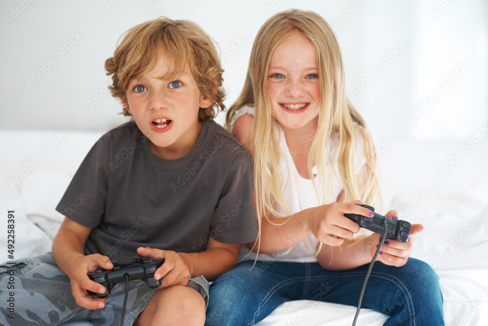 兄弟姐妹的亲密关系。年幼的兄弟姐妹坐在沙发上玩电子游戏。