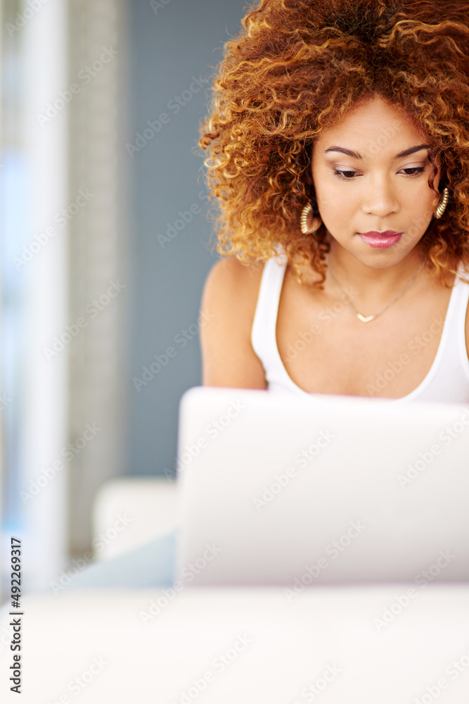 在内心与外界保持联系。一名年轻女子在沙发上使用笔记本电脑的照片