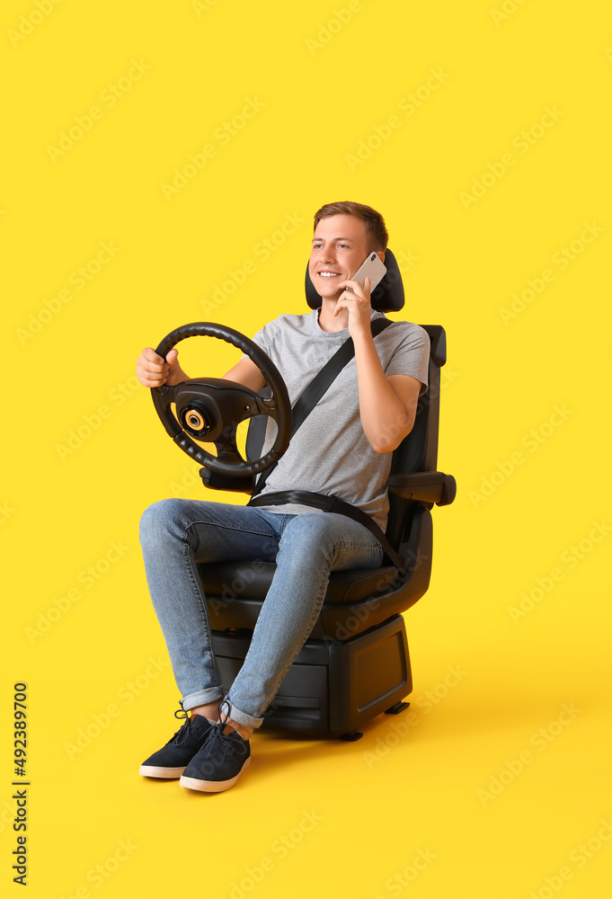 坐在汽车座椅上、方向盘在彩色背景下通过电话交谈的男子