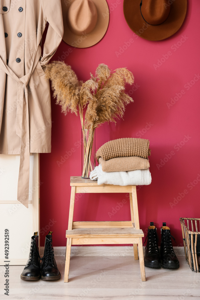 大厅粉色墙壁附近的暖毛衣和花瓶的脚凳