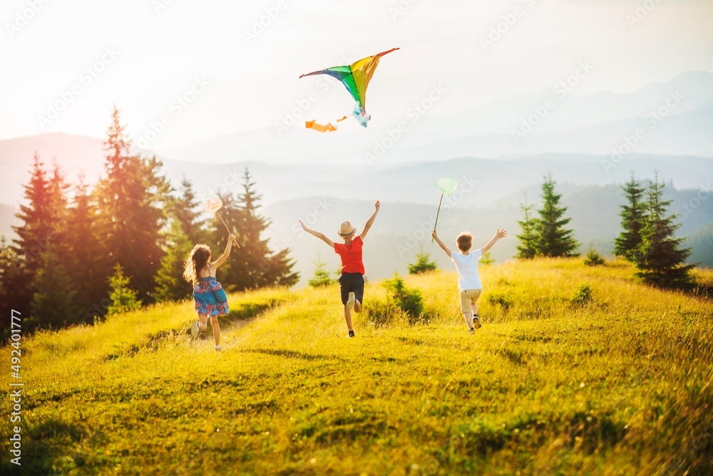 日落时分，三个孩子在山上玩风筝和蝴蝶渔网。暑假快乐。