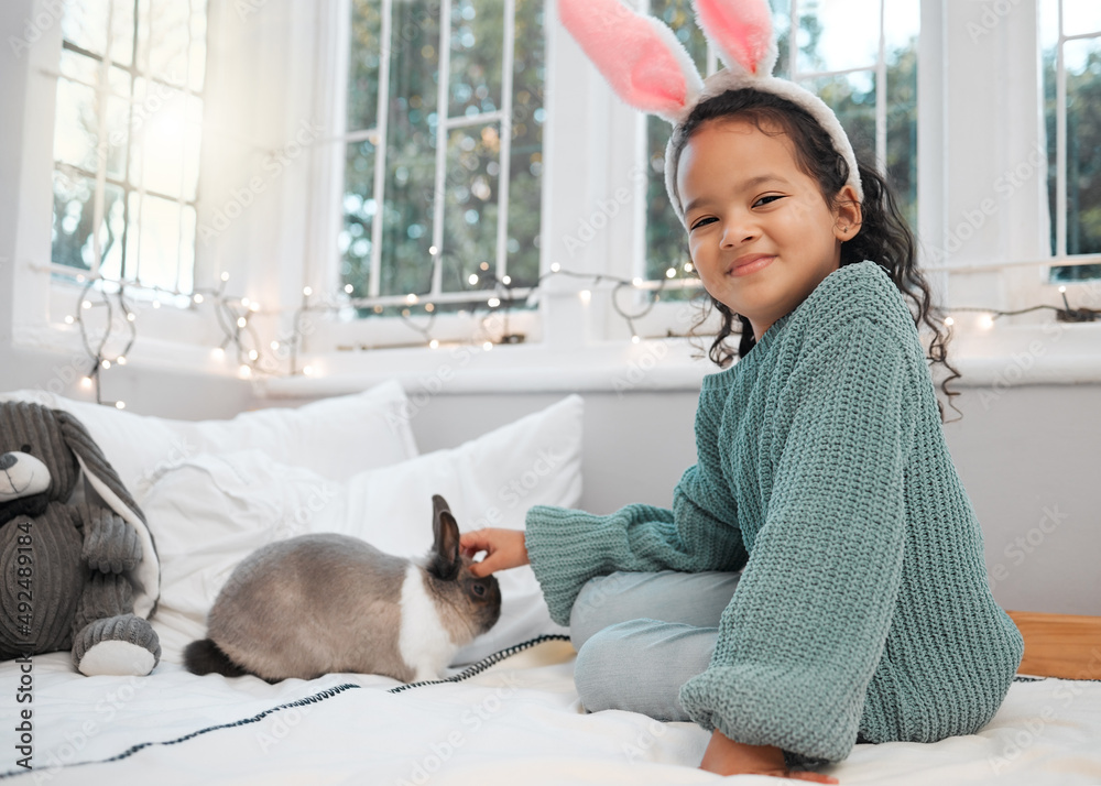 Look, were matching. Shot of an adorable little girl sitting on her bed and bonding with her pet rab