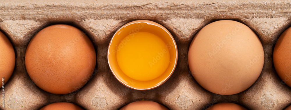 在黄色餐桌背景上分离的新鲜棕色鸡蛋。