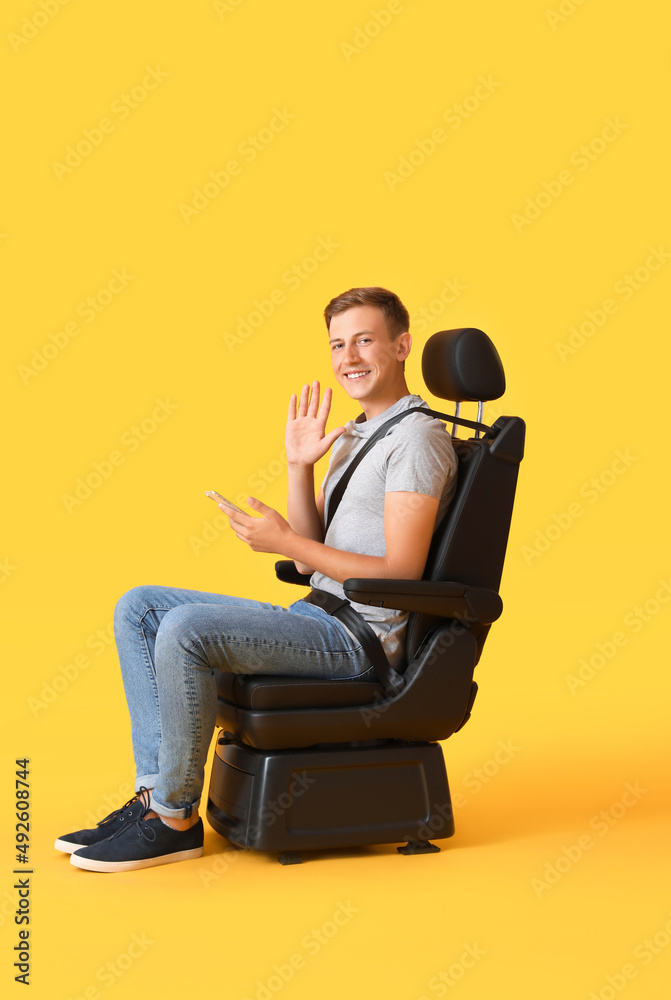 男子坐在汽车座椅上，背景为彩色手机
