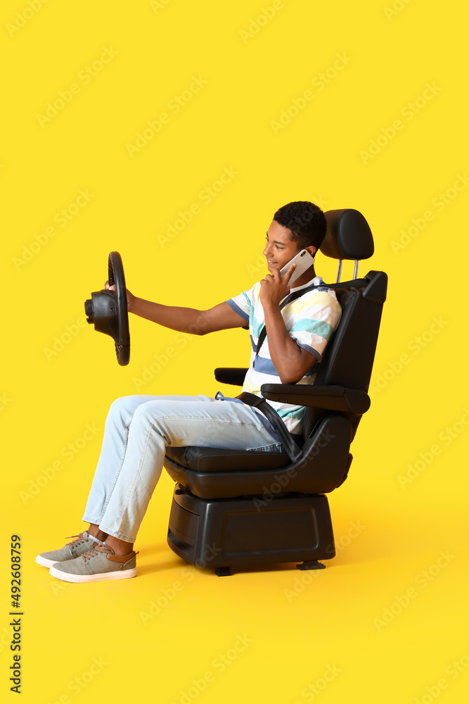 非裔美国人坐在汽车座椅上，方向盘在彩色背景下通过电话交谈