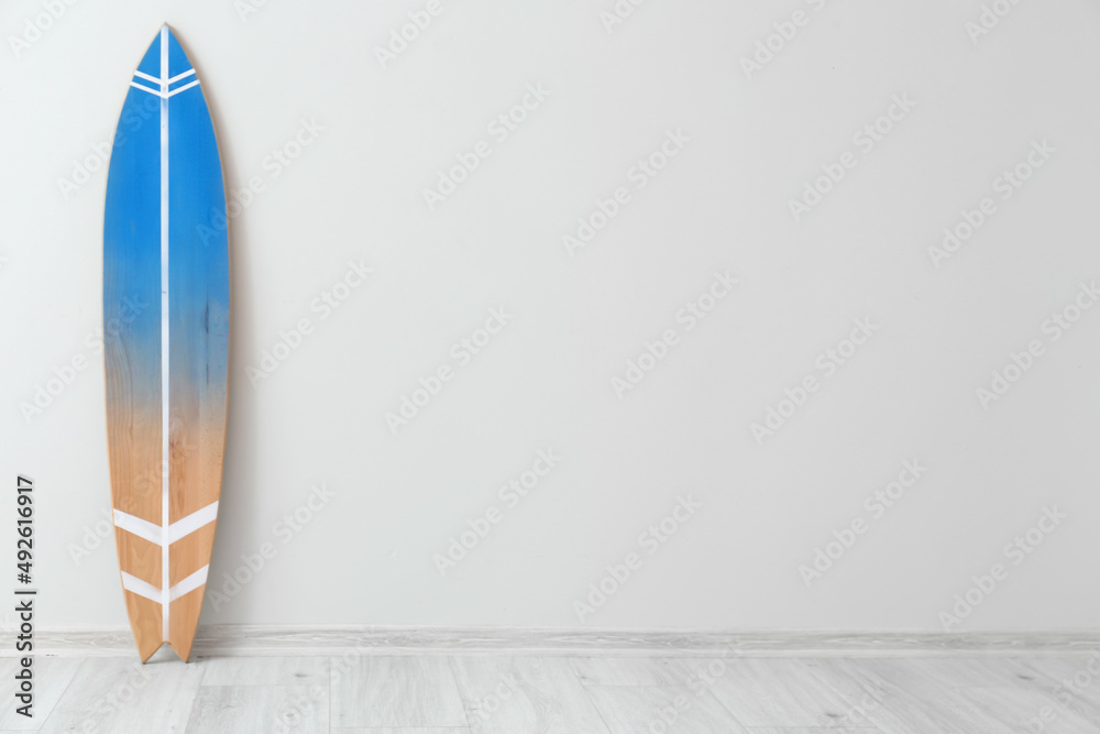 Wooden surfboard near light wall