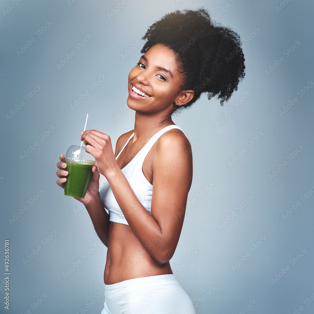 我一天都不能没有绿色果汁。一个漂亮的年轻女人喝绿色果汁的工作室镜头