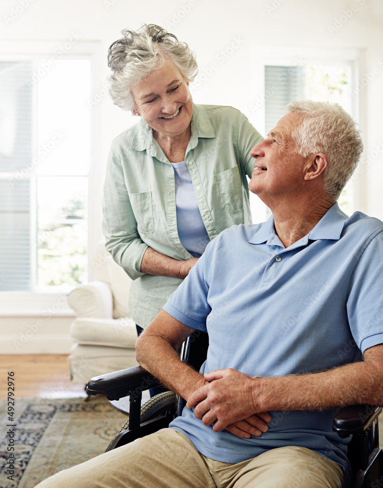 在冬天互相关爱。一位坐在轮椅上微笑的老人和他的妻子的照片
