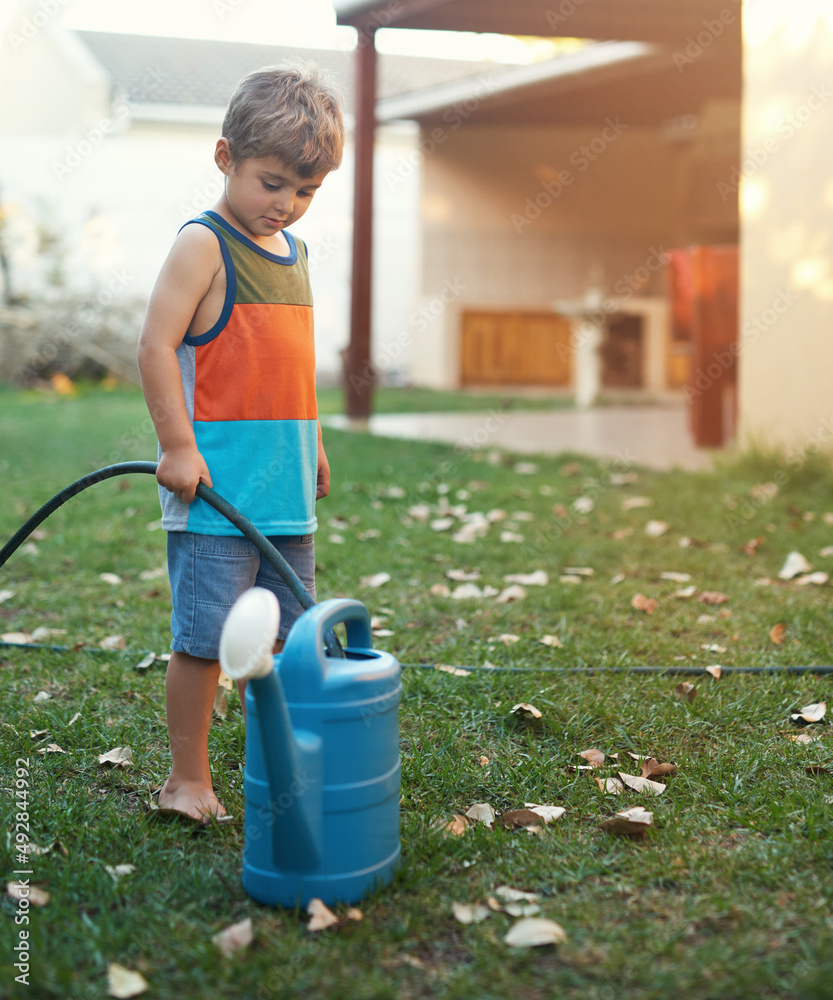关爱自然。一个小男孩用软管装满水罐的镜头。
