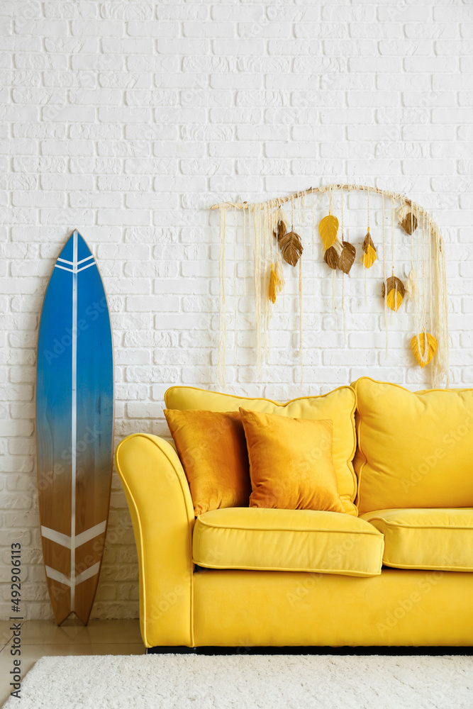 白色砖墙附近舒适的沙发和冲浪板