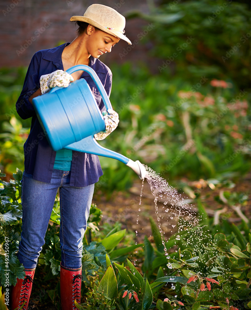 让它下雨。一个年轻女人给花园浇水的镜头。