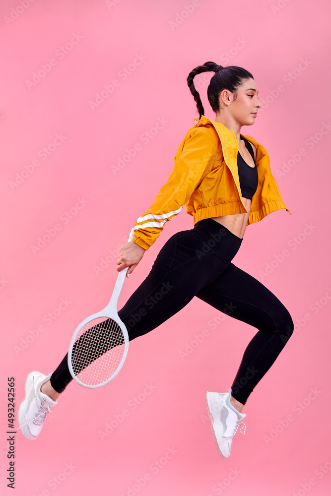 网球场在召唤我，我必须走了。一个运动型年轻女子拿着10英镑跳跃的工作室镜头