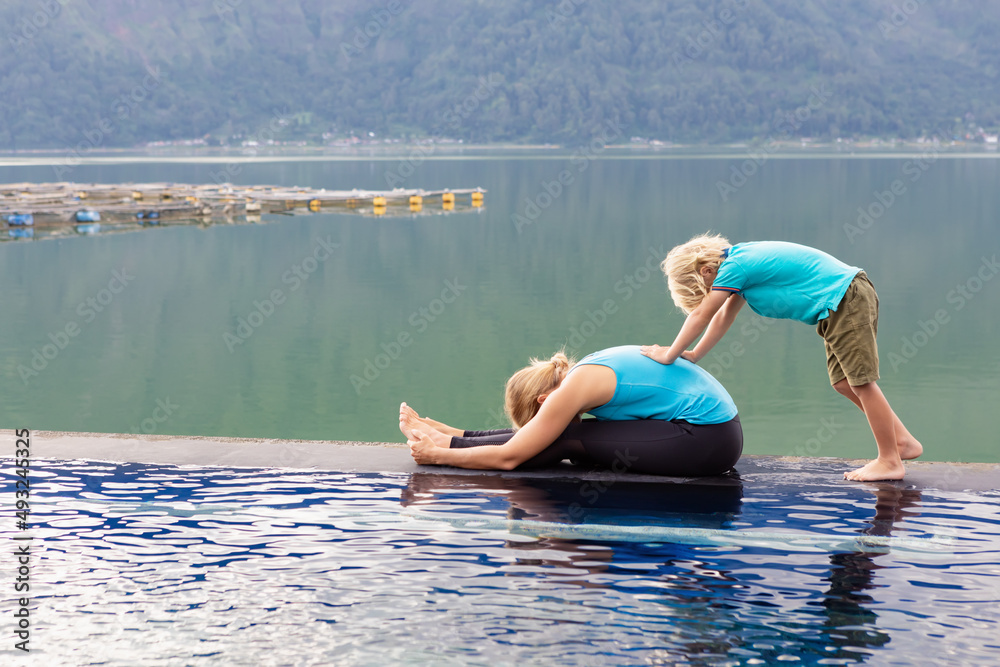 活跃的女性练习瑜伽，在泳池边伸展身体以保持健康。坐成弯曲姿势