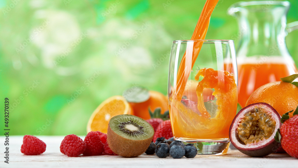 Multivitamin juice pouring into glass. Fresh orange juice with oranges fruit on wooden table.