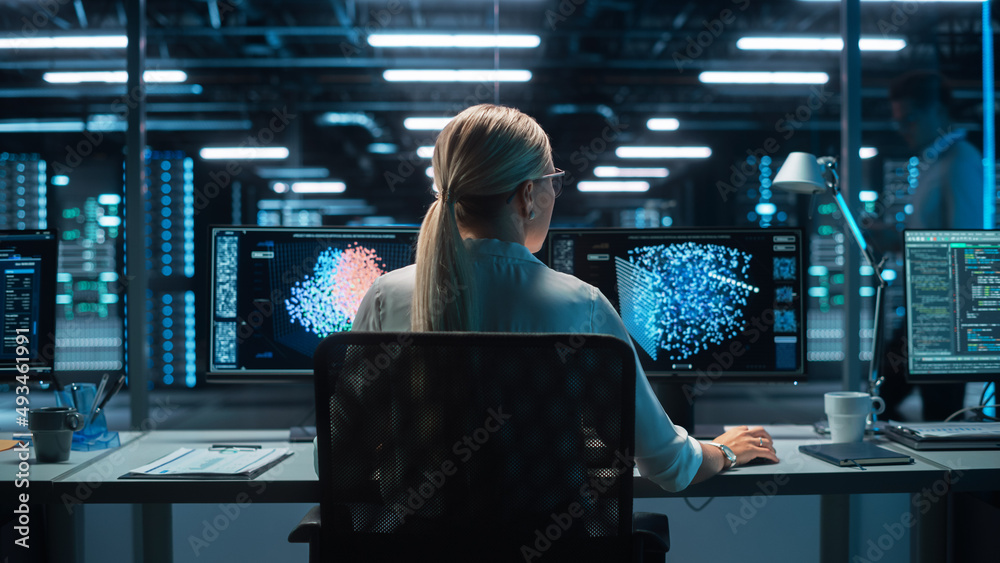 Futuristic Concept: Female Computer Engineer Looking on the Two Displays while Working on the Comput